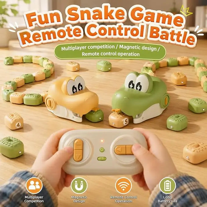 A children's remote-controlled snake game shown on a wooden tabletop, with two cartoonish yellow and green snake cars racing around food pieces. A pair of hands holds a white remote control in the foreground.